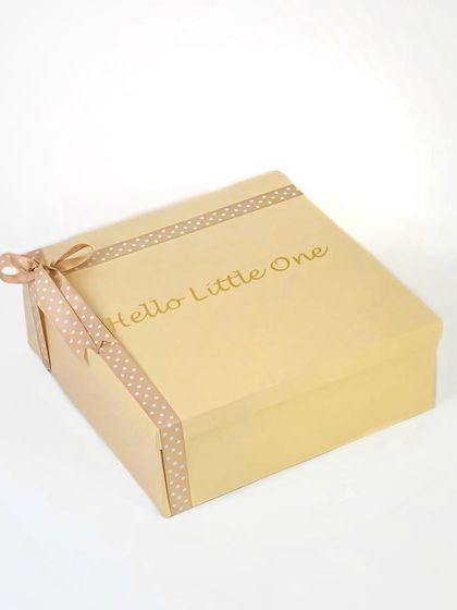 The exterior of a simple and elegant baby gift box with 'Hello Little One' in gold foil. This shot focuses on the premium packaging, which is an important part of the gifting experience.