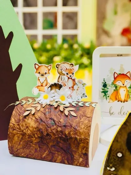 A close-up of the woodland decor, with tiny fox cutouts on a log and a small tree prop, adding to the miniature forest scene.