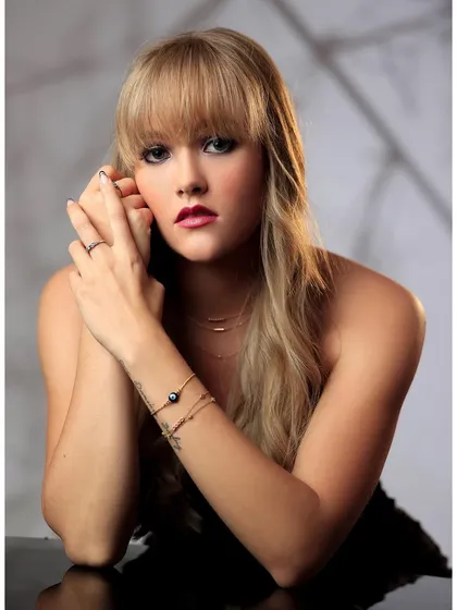 A classic beauty headshot of a model with soft lighting and a textured background.