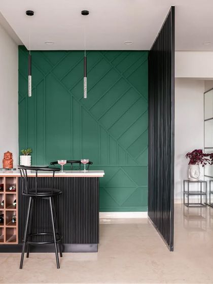 I created this happening bar area in a previously dead corner of the living room. A bold green geometric accent wall, a compact fluted bar counter, and an open wine rack make this a stylish spot for entertaining.