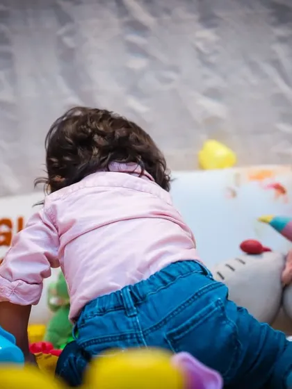 A shot from behind as a toddler crawls towards his toys, capturing a sense of adventure and exploration.
