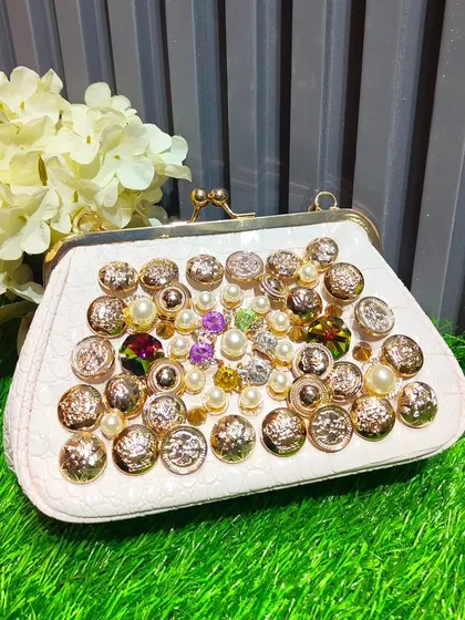 The same embellished clutch design in a white and gold colorway, offering a brighter but equally unique accessory option.