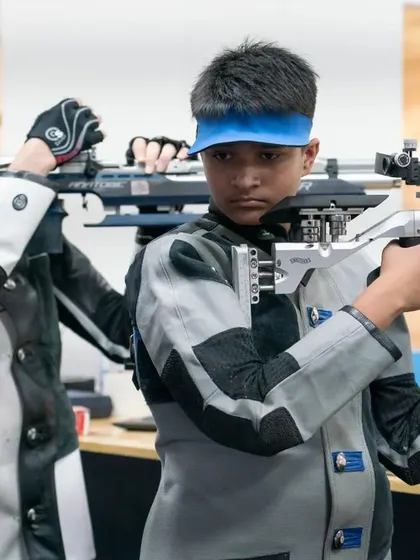 Two young rifle shooters getting into position. We emphasize peer learning and a supportive team environment, even during intense competitions.
