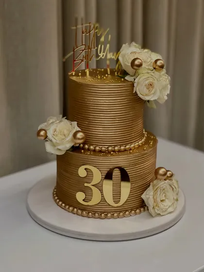 This two-tiered golden cake is one of my most requested designs for milestone birthdays. Here it is for a 30th birthday, featuring a ribbed texture, fresh white roses, and delicate pearl details.