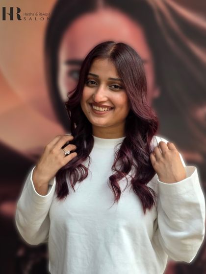 A happy client showing off her new burgundy highlights. The color complements her skin tone beautifully, and the soft styling brings out the dimension in her hair.