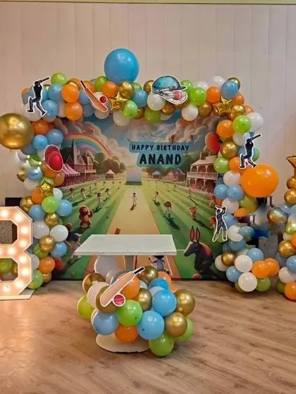 A cricket-themed 8th birthday party with a custom backdrop showing a cricket pitch, a balloon arch, and a marquee number '8'.