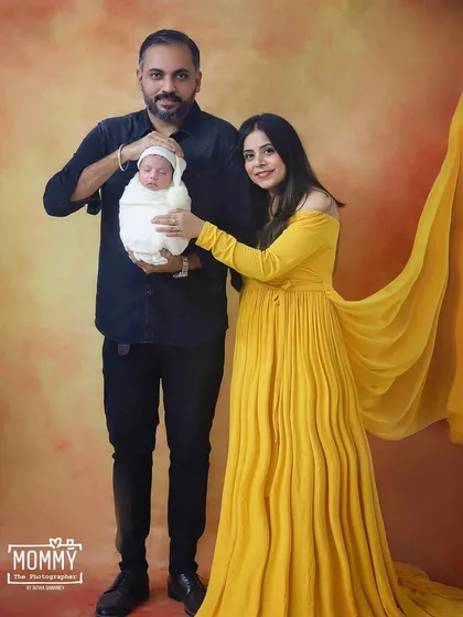 A sweet family photo where the parents are holding their tiny newborn together. It’s a classic pose that beautifully documents the beginning of their journey as a family of three.