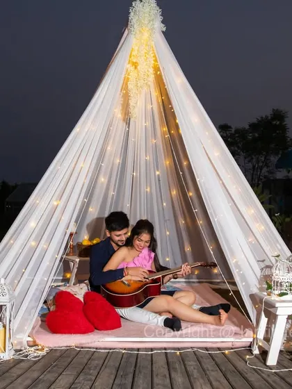 We create cozy and intimate atmospheres for your shoot, like this beautiful night setup. A fairy-lit teepee, complete with lanterns and a mandolin prop, sets the stage for a warm and romantic pre-wedding photograph.