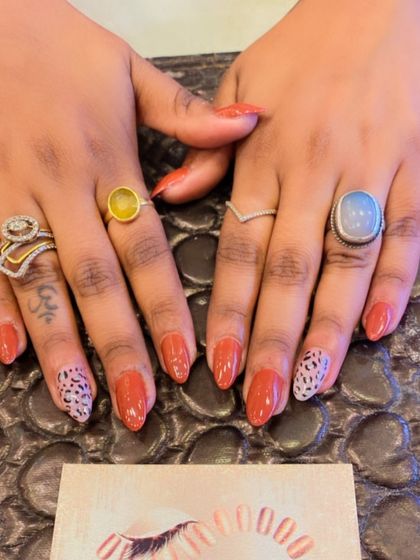 A chic animal print design on almond-shaped nails. The burnt orange polish is paired with accent nails featuring a classic leopard print.