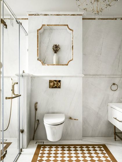 A detail shot of a luxurious master bathroom, featuring a scalloped marble niche with brass trim. The design showcases our meticulous attention to detail and our ability to create beautiful, functional storage solutions.