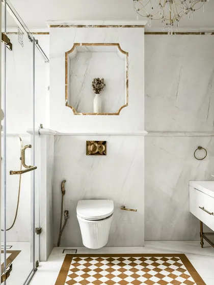 A detail shot of a luxurious master bathroom, featuring a scalloped marble niche with brass trim. The design showcases our meticulous attention to detail and our ability to create beautiful, functional storage solutions.