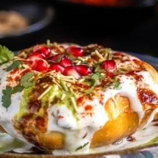 This is our take on the classic Raj Kachori, a feast in itself. A large, crispy kachori is filled with delicious toppings like yogurt, tangy chutneys, sev, and pomegranate seeds for a burst of flavor and texture in every bite.