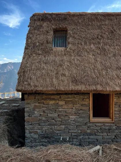 A close-up of the traditional thatch roof and local stone wall at our Panchachuli guesthouse project. The texture and irregularity of the materials are celebrated, reflecting a commitment to handmade construction and authentic character.