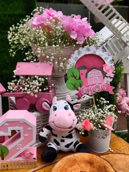 A collection of our custom-made farm props, including a plush cow, a personalized sign, and a decorative number '2', all arranged to create a charming vignette that captures the spirit of the barnyard theme.