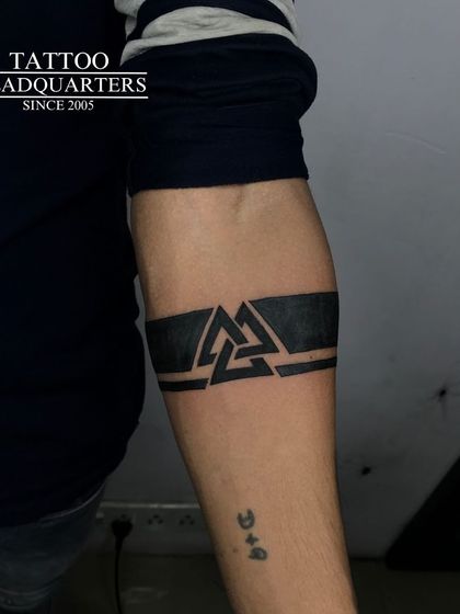 A solid black armband with a Valknut symbol integrated into the center, a powerful and popular geometric design.