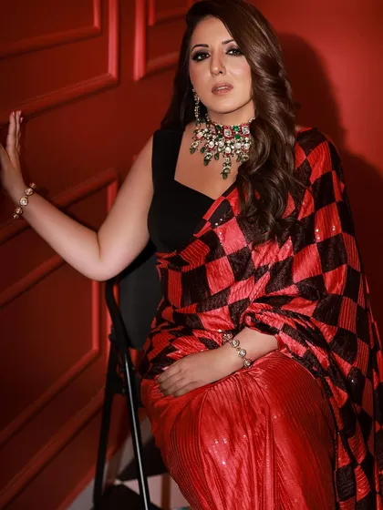 A seated pose that exudes confidence and style. The combination of the modern saree, smokey eye makeup, and heavy necklace creates a powerful fashion statement.