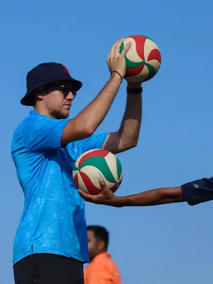 Guiding a player's hands to teach the feel of a proper set. This tactile coaching helps build muscle memory.