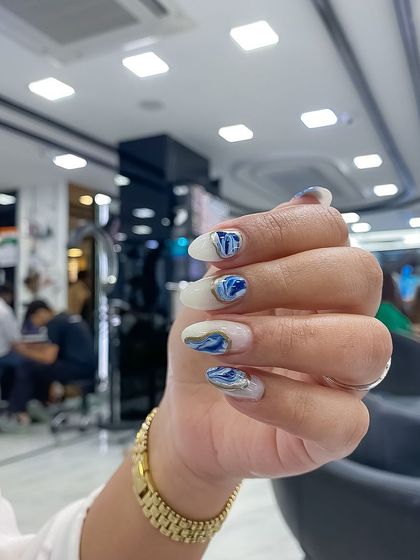 A close-up of the trending metallic Korean marble nails, featuring beautiful swirls of blue and white with gold accents.