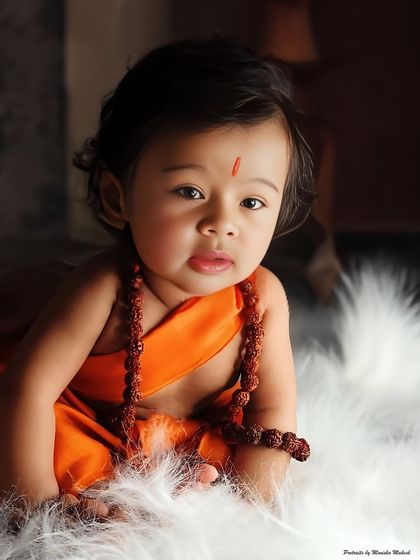 A beautiful portrait of a baby dressed as Little Rama, looking directly at the camera with wide, innocent eyes.