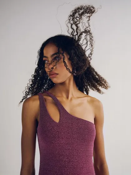 A studio portrait for Melova, capturing the movement of the model's curly hair. The clean background and simple styling keep the focus on her natural beauty.