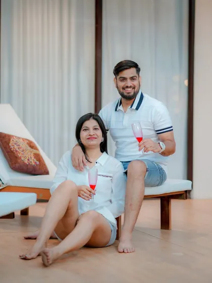 A relaxed and intimate moment at a modern resort-style location. This shot captures the couple enjoying a quiet celebration with champagne, showcasing a casual yet sophisticated pre-wedding vibe.