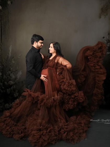 A dramatic and romantic couple's portrait. The rich brown gown with its flowing frills creates a stunning silhouette against the dark, moody backdrop.