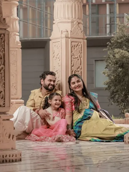 A family portrait set against grand, carved stone pillars, blending natural light with beautiful architecture.