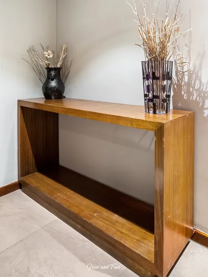A minimalist wooden console table in a hotel corridor, styled with simple vases. The clean lines and warm wood create a simple yet elegant welcome for guests at Sinclairs Hotel, Ooty.