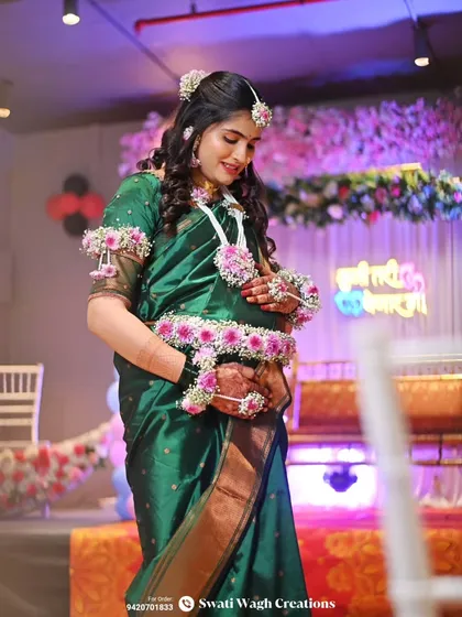 A full view of the baby shower stage and our client looking radiant in her floral jewellery. The background decor enhances the floral theme.