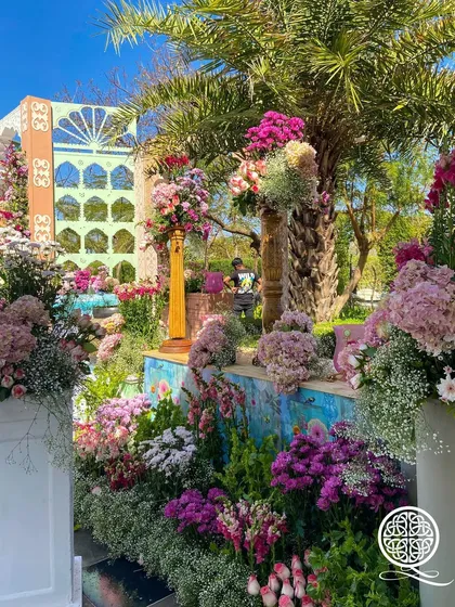 Another view of the 'City of Flowers' decor, with vibrant floral arrangements set against a backdrop of palm trees and decorative panels, showcasing a rich tapestry of color and texture.