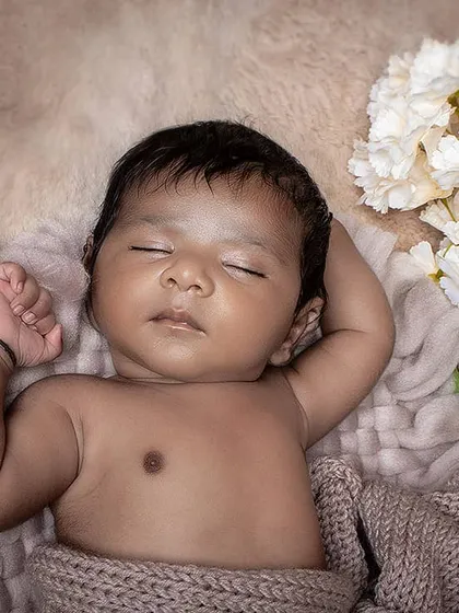 A peaceful close-up of a sleeping newborn, with a focus on their serene expression. The neutral tones of the blanket and background keep the image soft and classic.