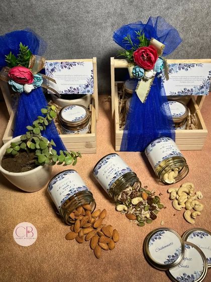 These return gift favours for a wedding are simple, elegant, and thoughtful. Each pinewood basket contains a succulent plant and jars of almonds, cashews, and mixed seeds, all wrapped in royal blue tulle.