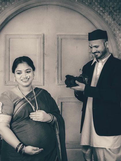 A candid shot of the couple sharing a smile as he pretends to review the photos on his camera. These playful interactions bring out the couple's personality even within a highly stylized studio environment.