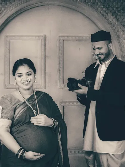 A candid shot of the couple sharing a smile as he pretends to review the photos on his camera. These playful interactions bring out the couple's personality even within a highly stylized studio environment.