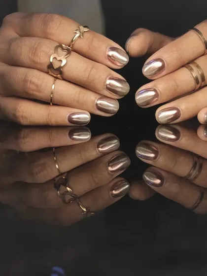 A chic and trendy rose gold chrome manicure on shorter, rounded nails.