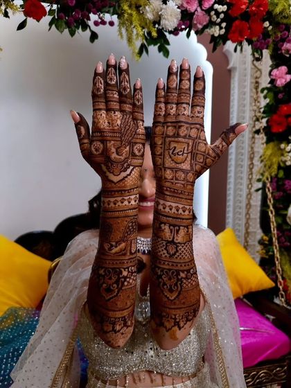 A bride holding up her hands to display the full glory of her symmetrical bridal mehandi.