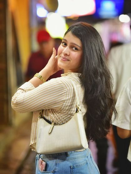 A sweet and gentle smile captured under the warm glow of the market lights. This pose is both inviting and charming, making for a lovely night portrait.