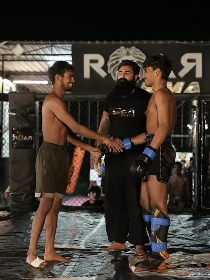 Respect before the battle. Two fighters touch gloves under the referee's watch before the bell rings, a tradition of sportsmanship in combat sports.