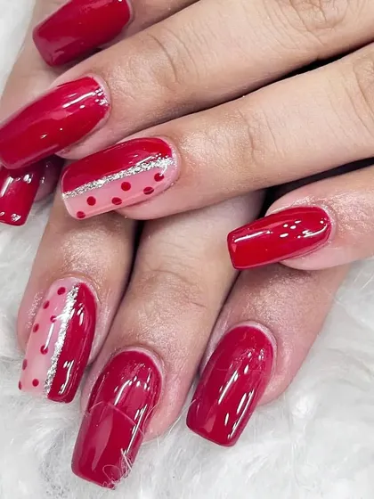 A classic red set with a fun twist, featuring accent nails with polka dots and a silver glitter stripe.