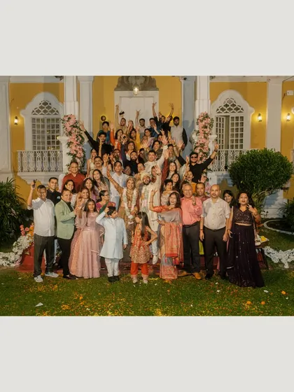 A fun and energetic group photo with all the wedding guests celebrating with the couple in front of their beautiful Goa venue.