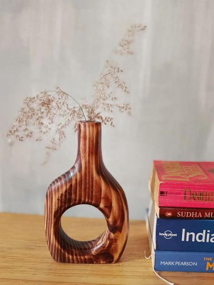 Our wooden vase styled on a desk next to a stack of books. It's a perfect, artistic touch for a study or reading nook.