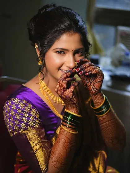A playful moment as the bride adjusts her nath. This candid shot captures her personality and the beautiful details of her traditional jewelry and makeup.
