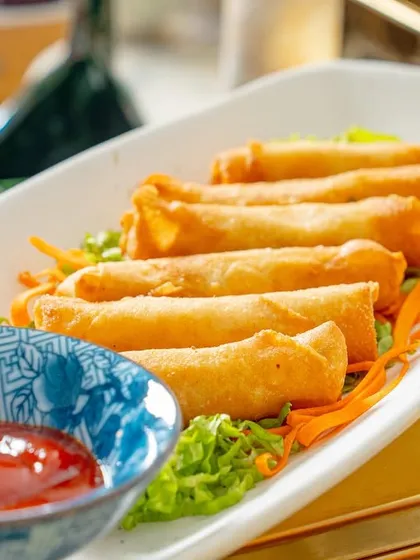 A platter of my crispy cigar rolls, filled with melted cheese and sweet corn, served with a side of ketchup. A perfect snack for any celebration.