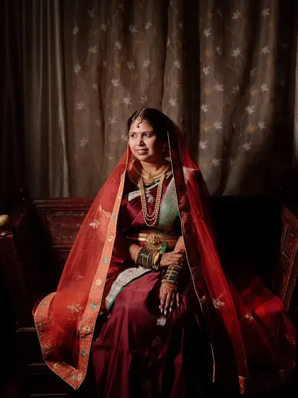 A classic and regal portrait of a Maharashtrian bride. The dramatic lighting and rich colors of her saree create a timeless, painting-like quality.