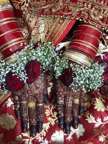 The bride's hands adorned with floral jewelry, highlighting the beautiful dark mehendi stain.