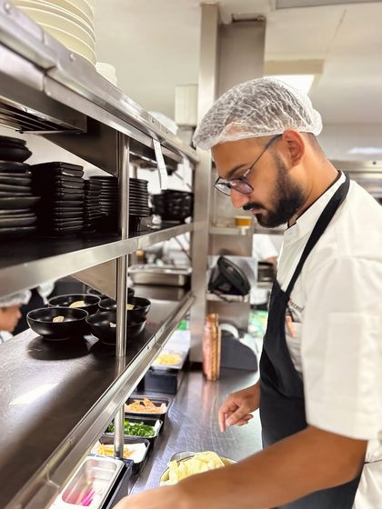 A chef on the line, focused on plating. Our kitchen is the ground zero for all our inventive dishes, a place of intense focus and creativity.