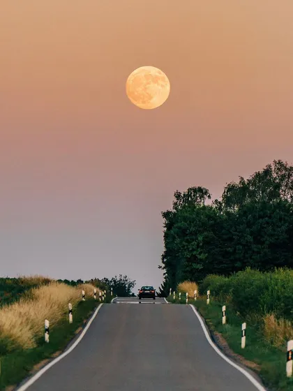 The 2022 Super Moon, also known as the Strawberry Moon in Sagittarius, sets behind a country road. I used a long lens to compress the perspective, making the moon feel immense and otherworldly.