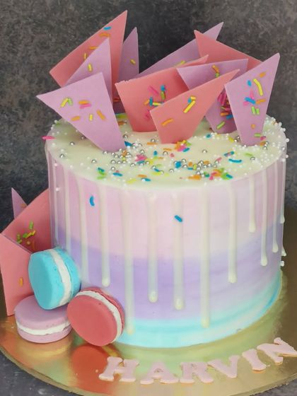 A beautiful pastel cake with chocolate shards and macarons. This fresh whipped cream chocolate cake has a modern and artistic design.
