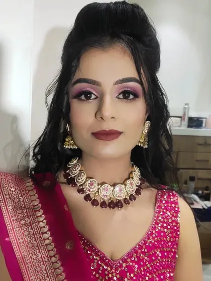 A beautiful sangeet look featuring dramatic pink and purple eye makeup and a bold lip color to match her vibrant pink outfit.