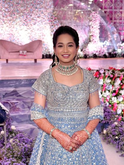 A smiling portrait against the grand floral backdrop of the reception stage.